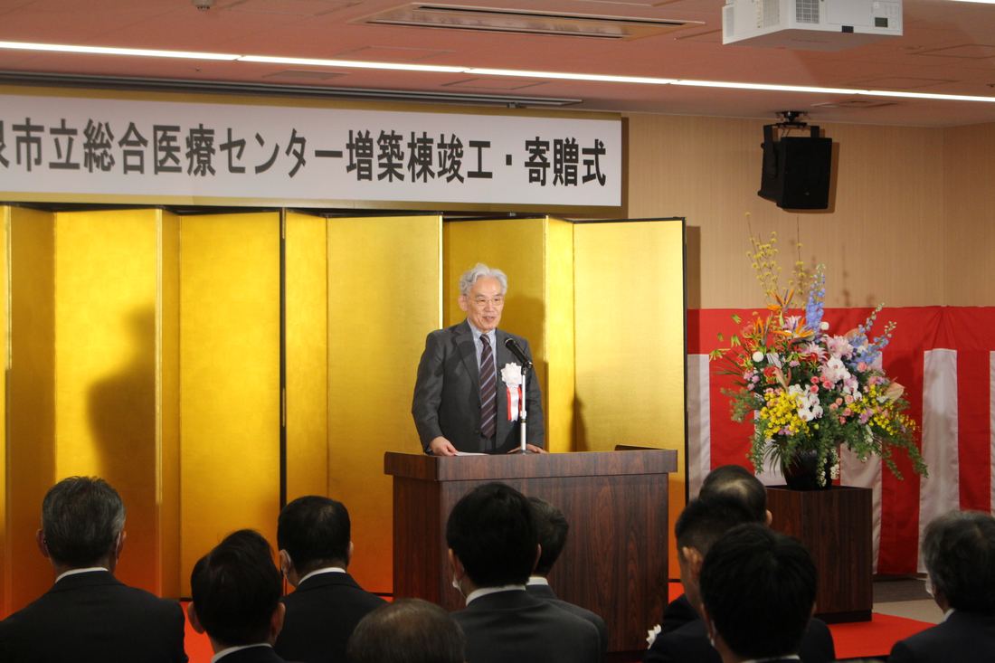 金屏風の前で挨拶が行われる竣工式・寄贈式の会場
