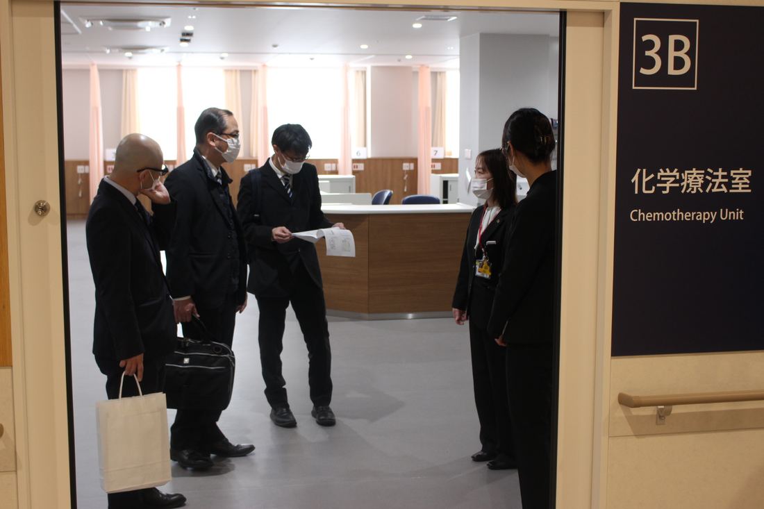 内覧会で化学療法室3Bの受付前を見学する来賓